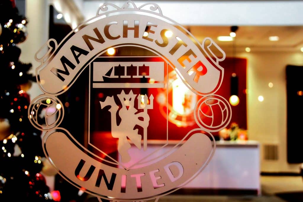 Close-up of Manchester United emblem etched on glass, showcasing iconic design indoors.