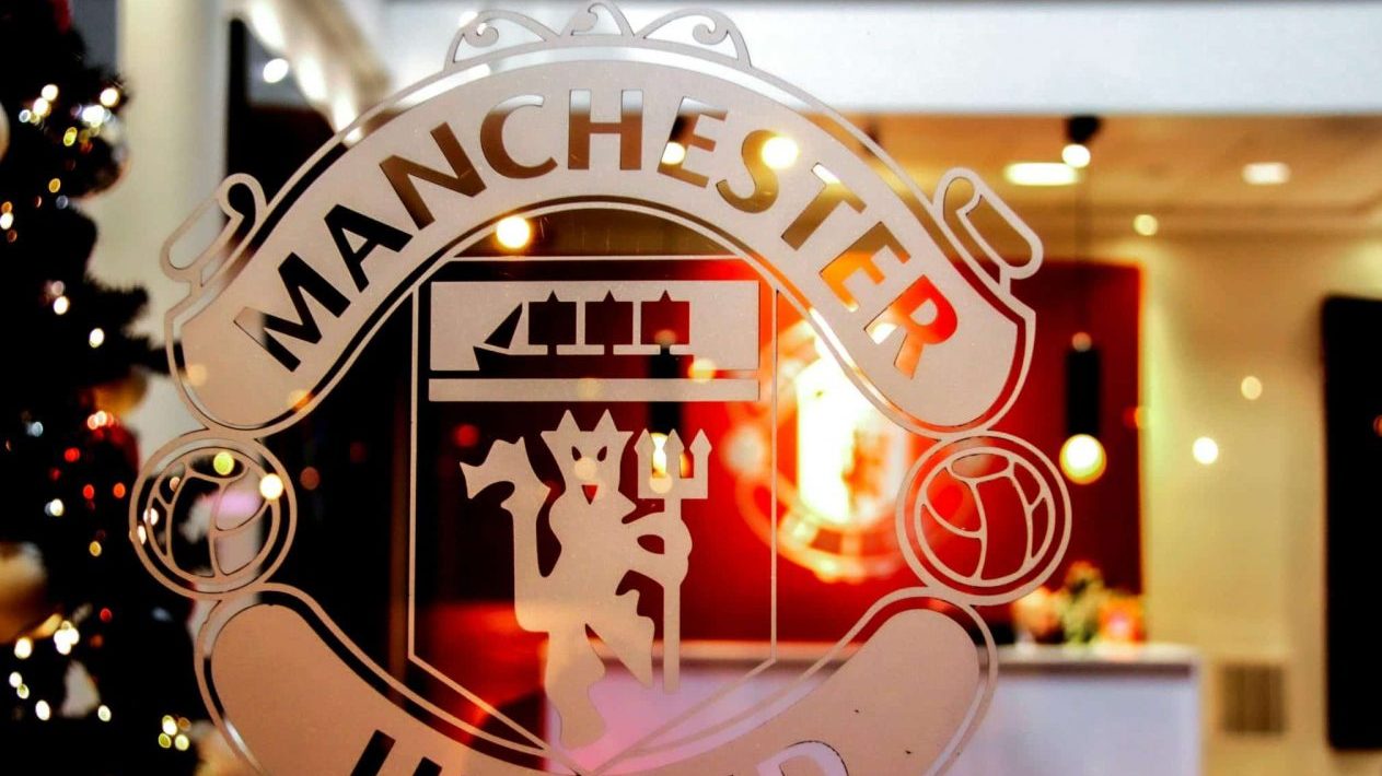 Close-up of Manchester United emblem etched on glass, showcasing iconic design indoors.
